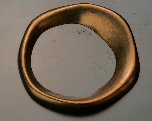 Gold-colored oval frame on a textured surface without any artwork inside