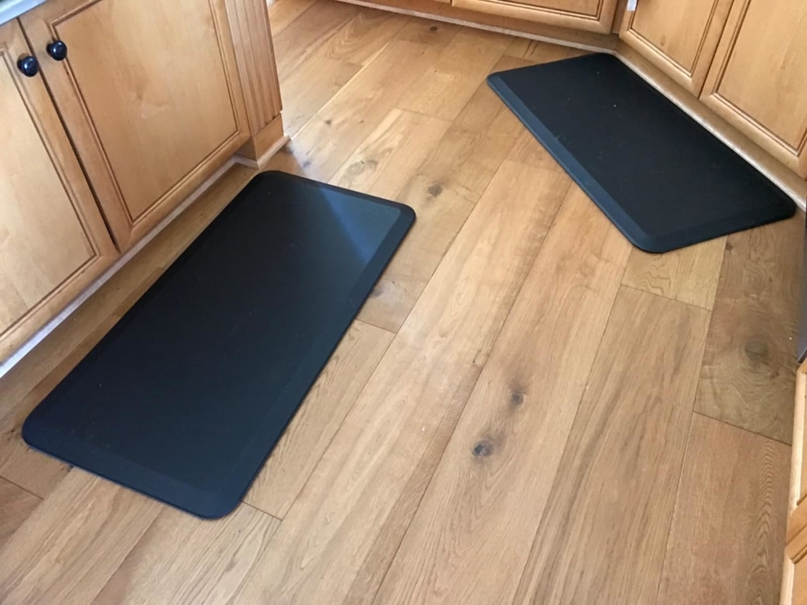 Two anti-fatigue kitchen mats on a wooden floor