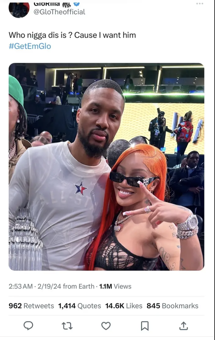Two individuals posing together, one in a basketball jersey, the other with vibrant red hair, sunglasses, and a black outfit
