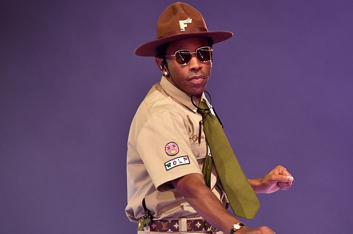 Person in scout-inspired outfit with hat, neckerchief, and badges; striking a pose