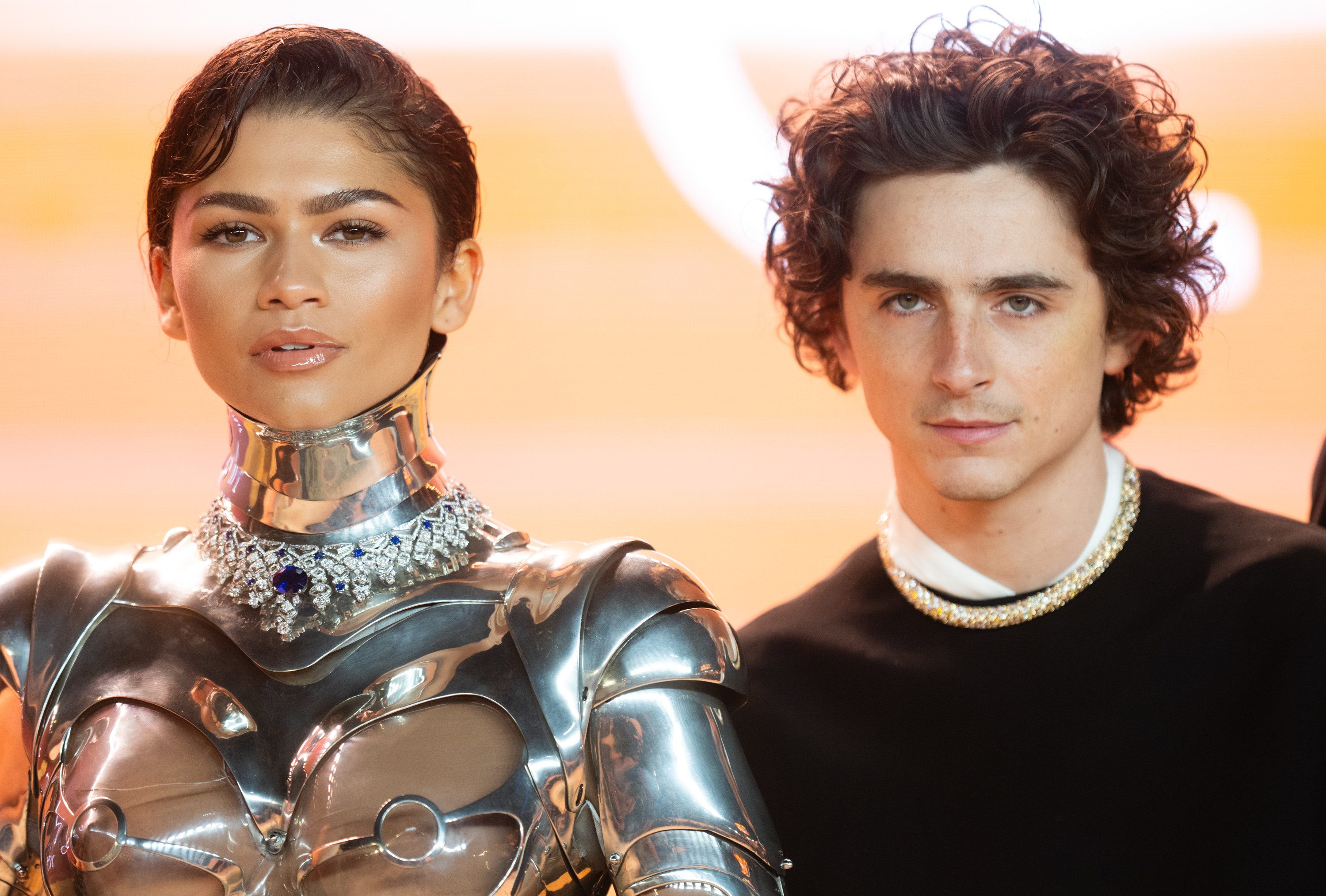 Zendaya in a metallic outfit and Timothée Chalamet in a sweater, standing side by side