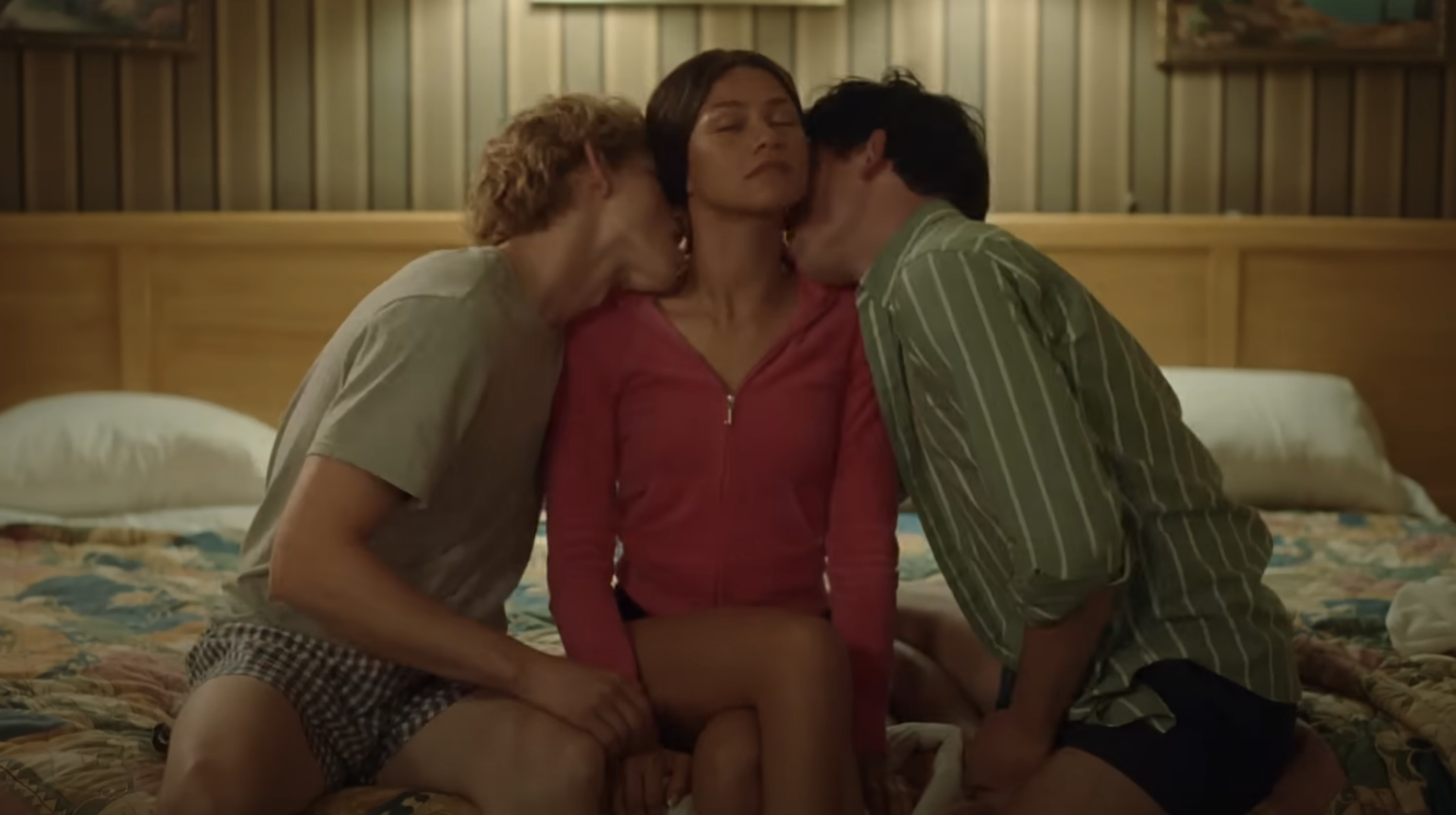 Mike Faist and Josh O&#x27;Connor kissing Zendaya on the neck as they sit on a bed in a scene from &quot;Challengers&quot;