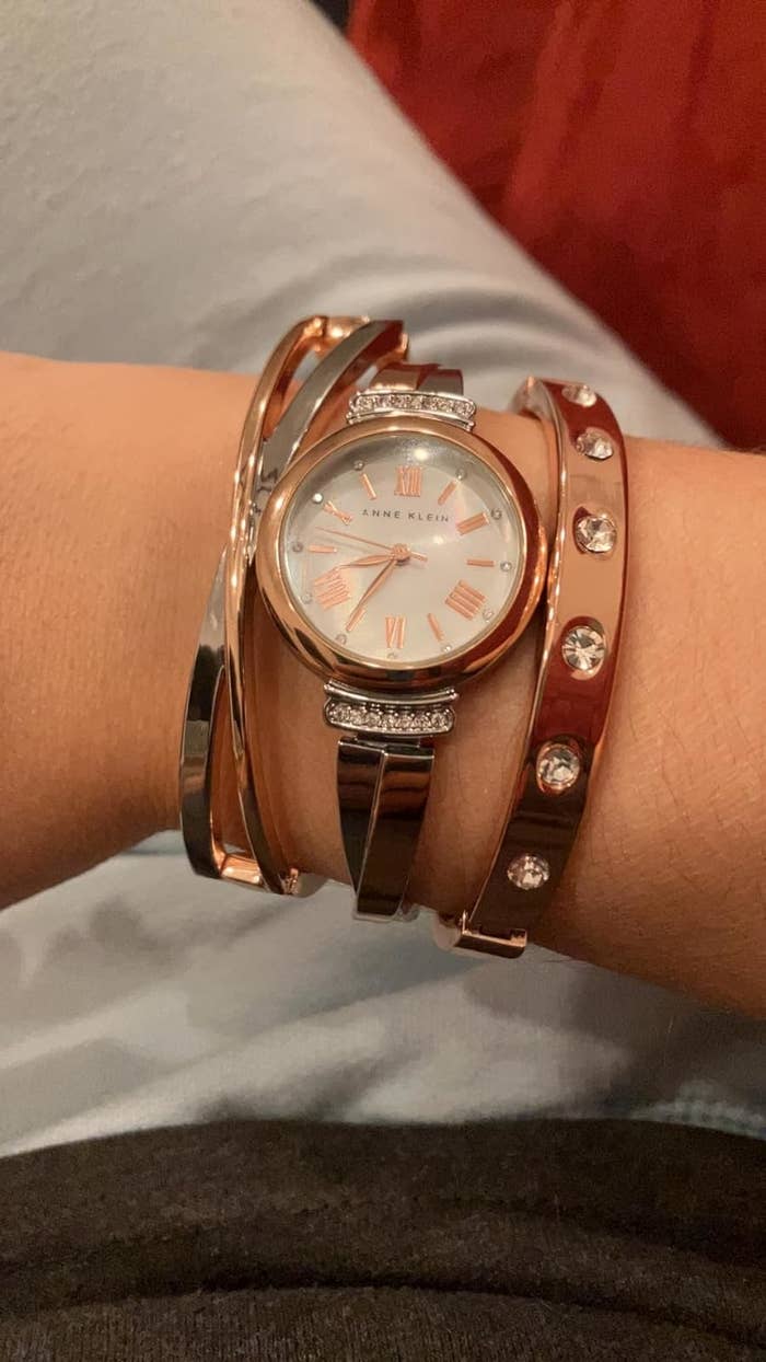 A wrist with a rose-gold watch and coordinating bracelets