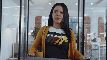 Woman in a graphic tee and yellow cardigan standing in an office environment
