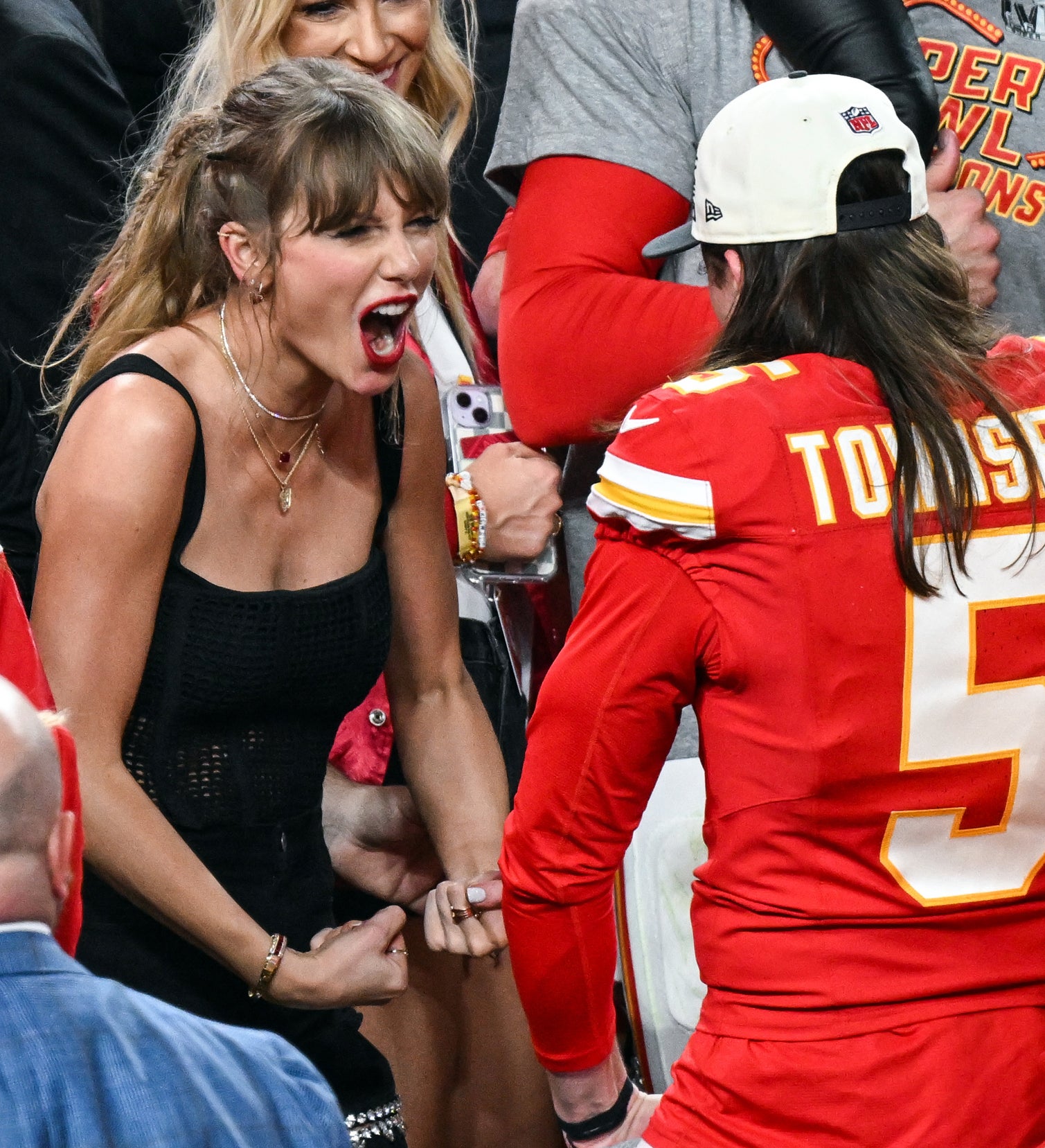 Taylor Swift in a top cheering with a person wearing a Kansas City Chiefs #15 jersey