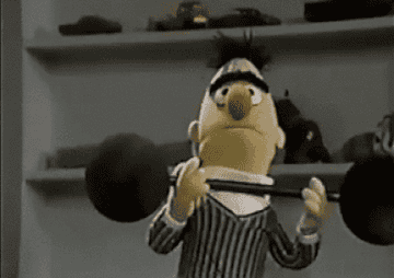 Bert from Sesame Street struggles to lift a barbell
