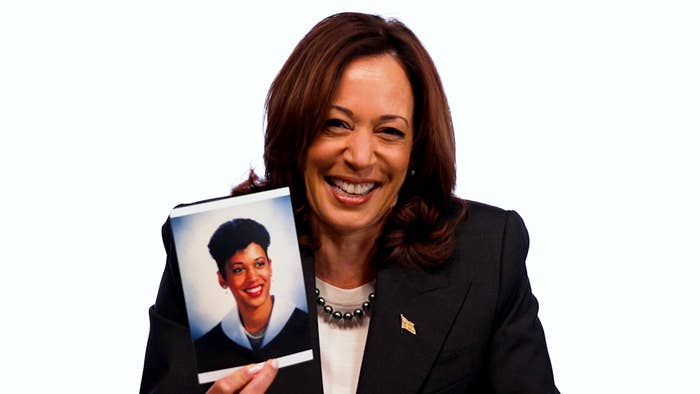 Kamala Harris smiling, holding an old photo of herself. She is wearing a suit and a pearl necklace