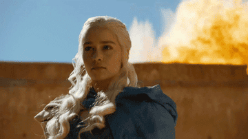 Daenerys Targaryen from Game of Thrones with a dragon exhaling fire in the background