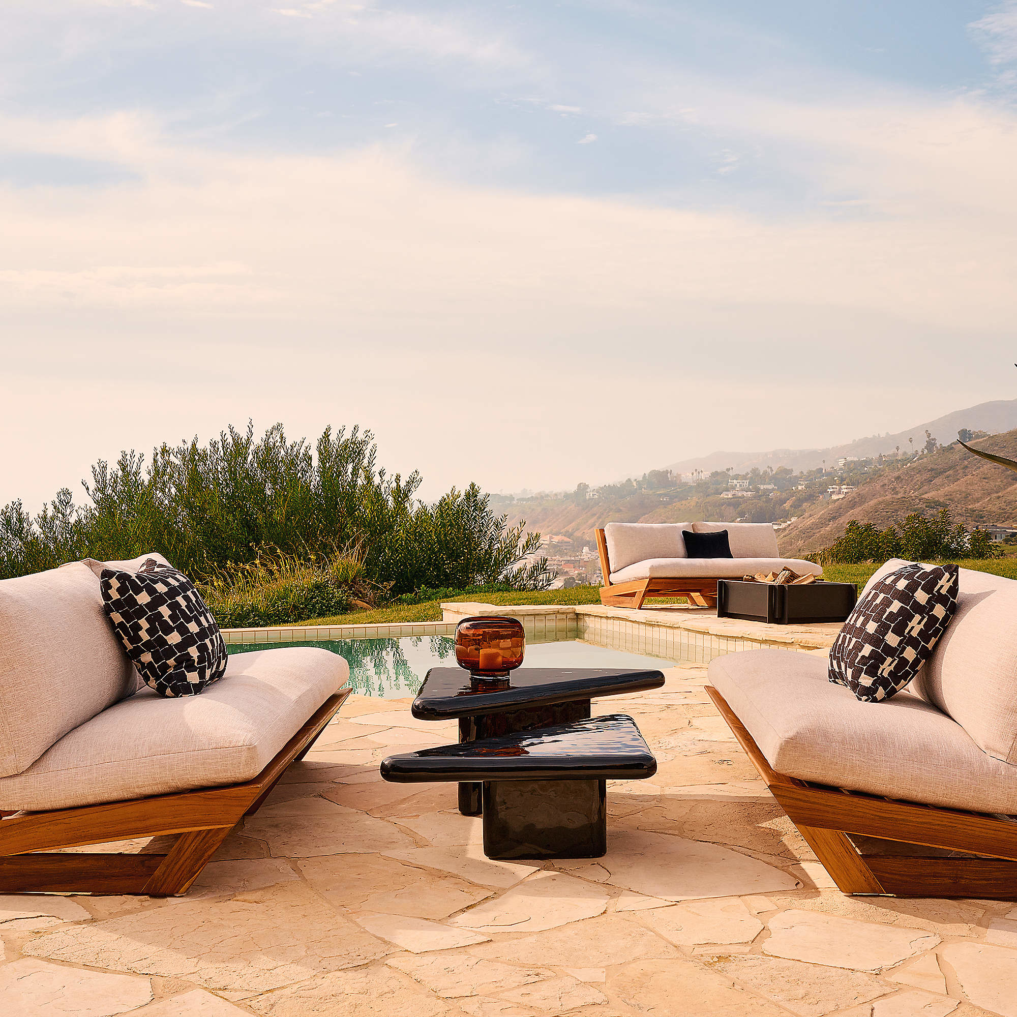 Luxury outdoor patio with low teak and cream upholstered loveseats