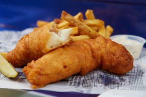 Fish and chips served with a lemon wedge and tartar sauce on newspaper