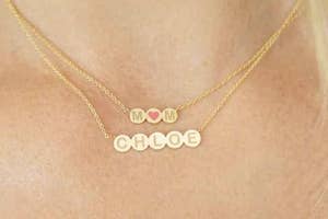 Necklace with "MOM" charm and "CHLOE" on a person