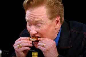 Conan O'Brien eating a chicken wing on Hot Ones