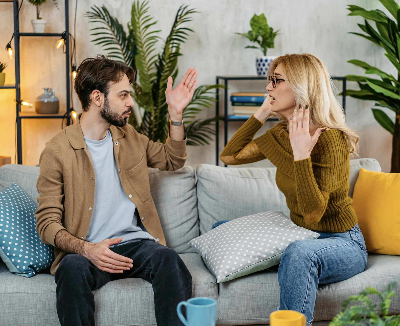 Two people having a conversation on a sofa with expressive hand gestures