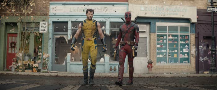 Characters Wolverine and Deadpool standing side by side in superhero costumes on a street