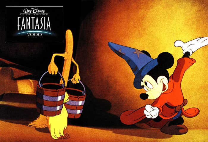 Mickey Mouse in &quot;Fantasia 2000&quot; wearing a wizard hat, carrying buckets alongside enchanted broom