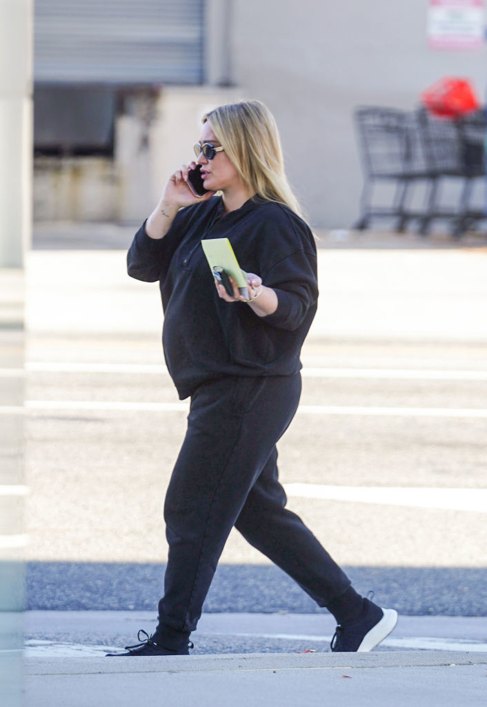 Hilary Duff in casual attire talking on the phone while walking on the sidewalk