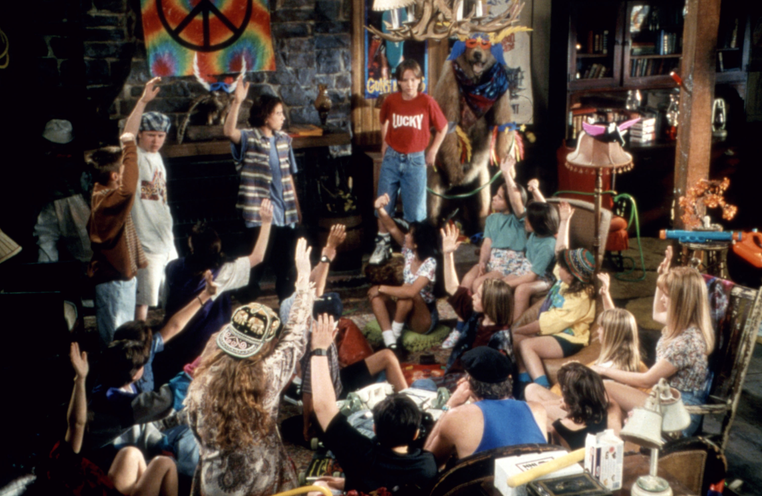 Cast of 'Camp Nowhere in a cabin setting with hands raised