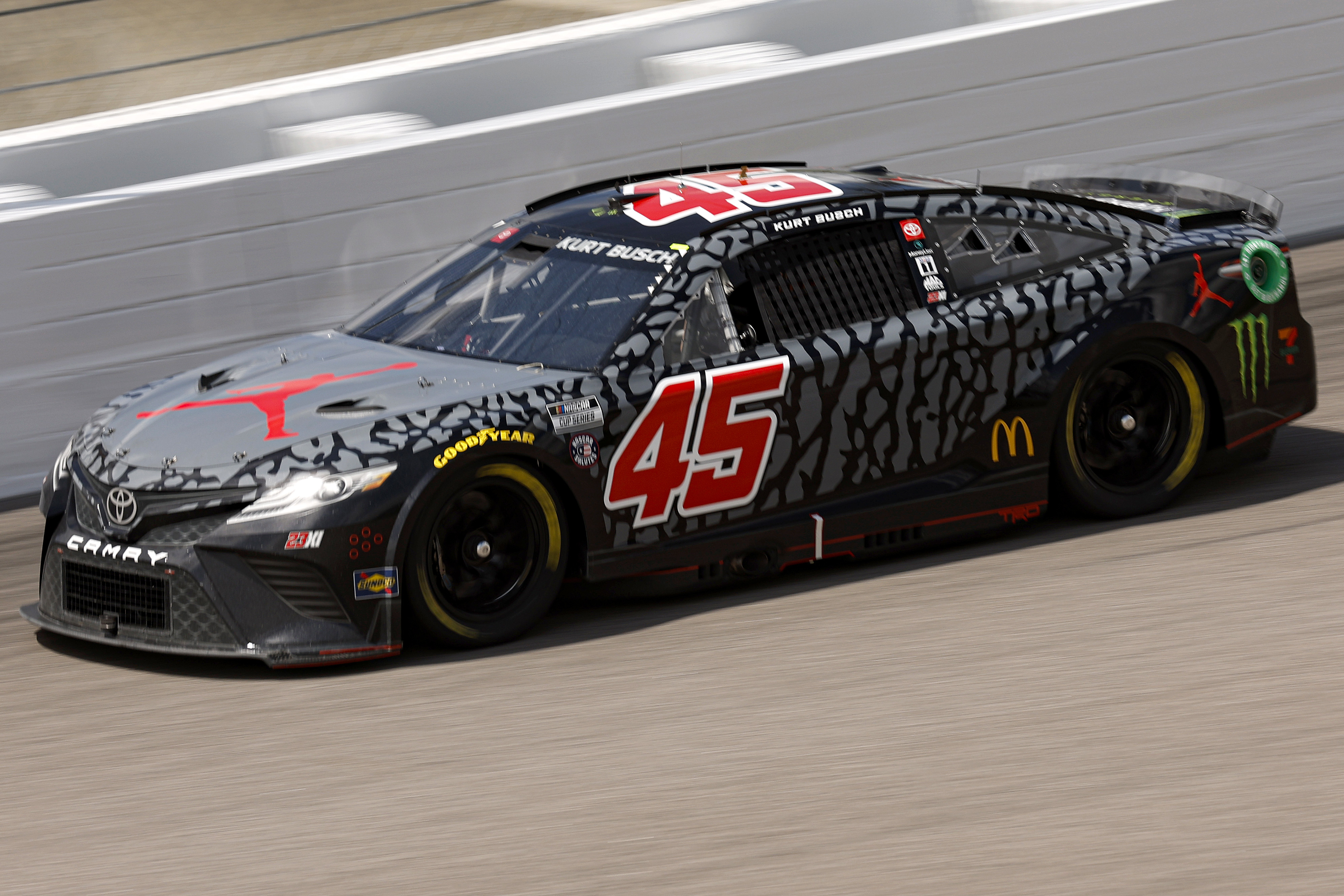A NASCAR vehicle with the number 45 and sponsor logos races on a track