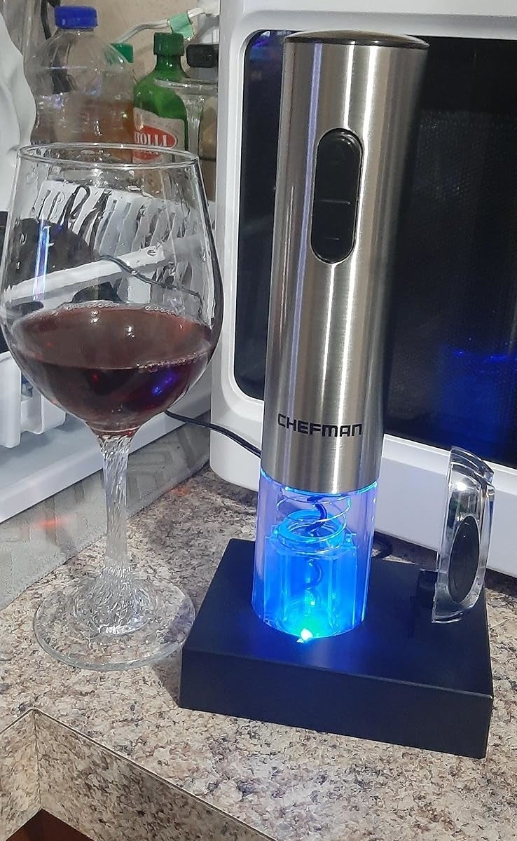 Electric wine opener by Chefman on countertop with a glass of wine next to it