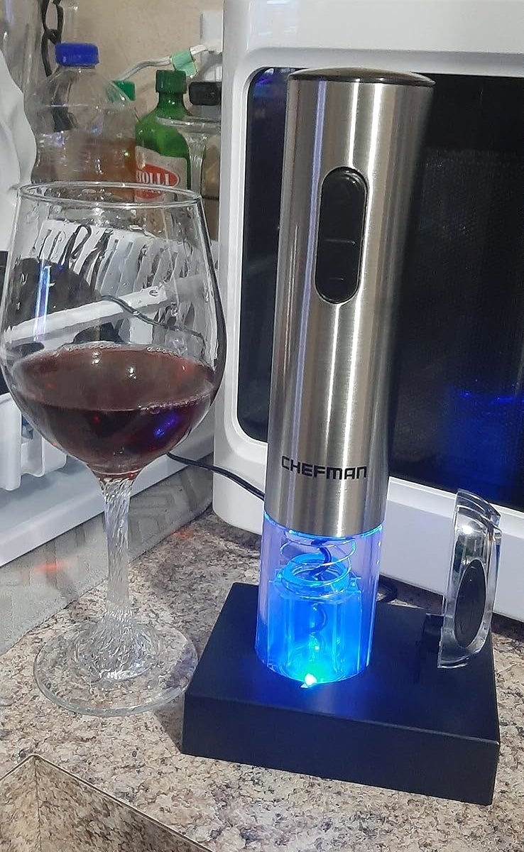Electric wine opener by Chefman on countertop with a glass of wine next to it