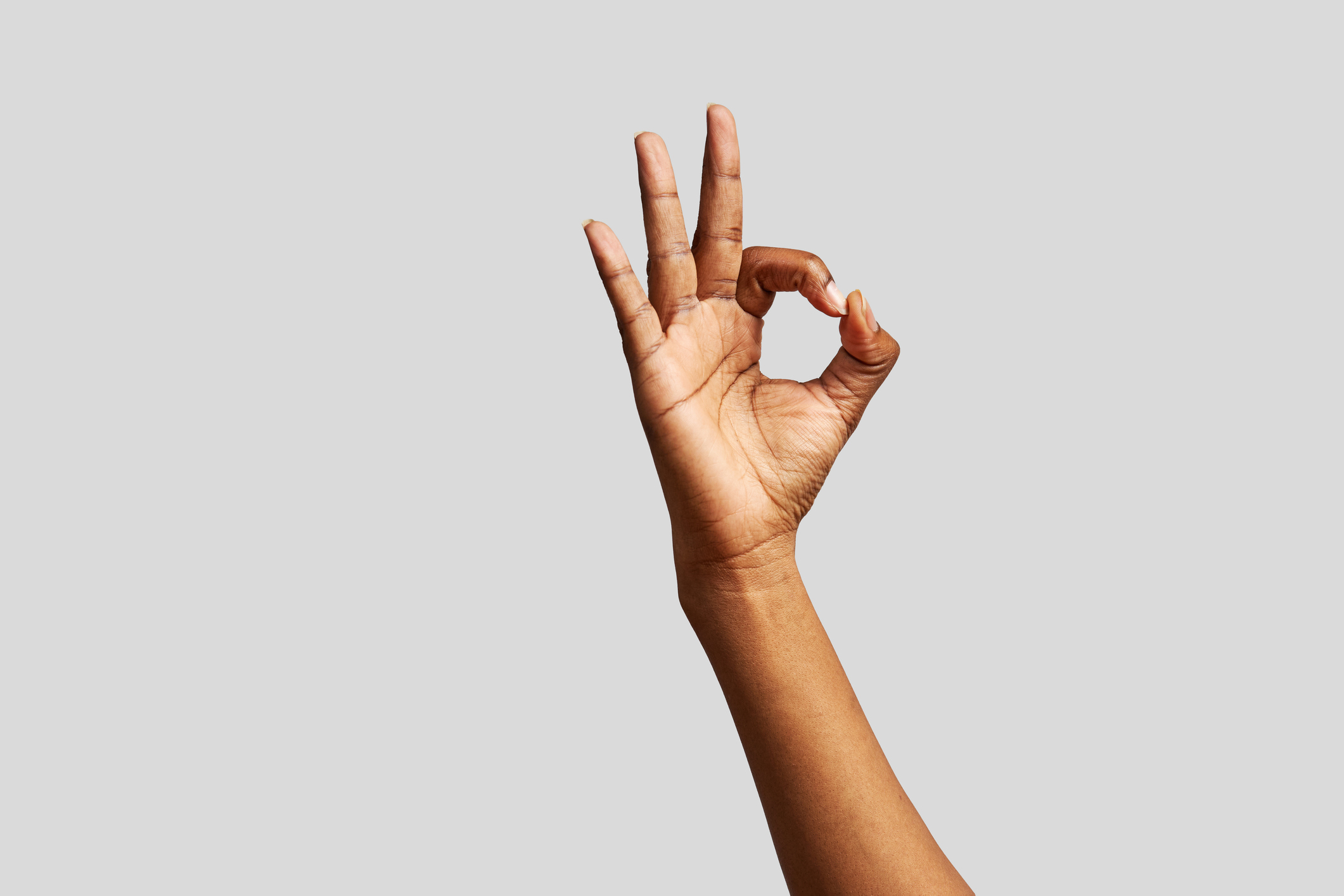 Hand making okay sign against a plain background