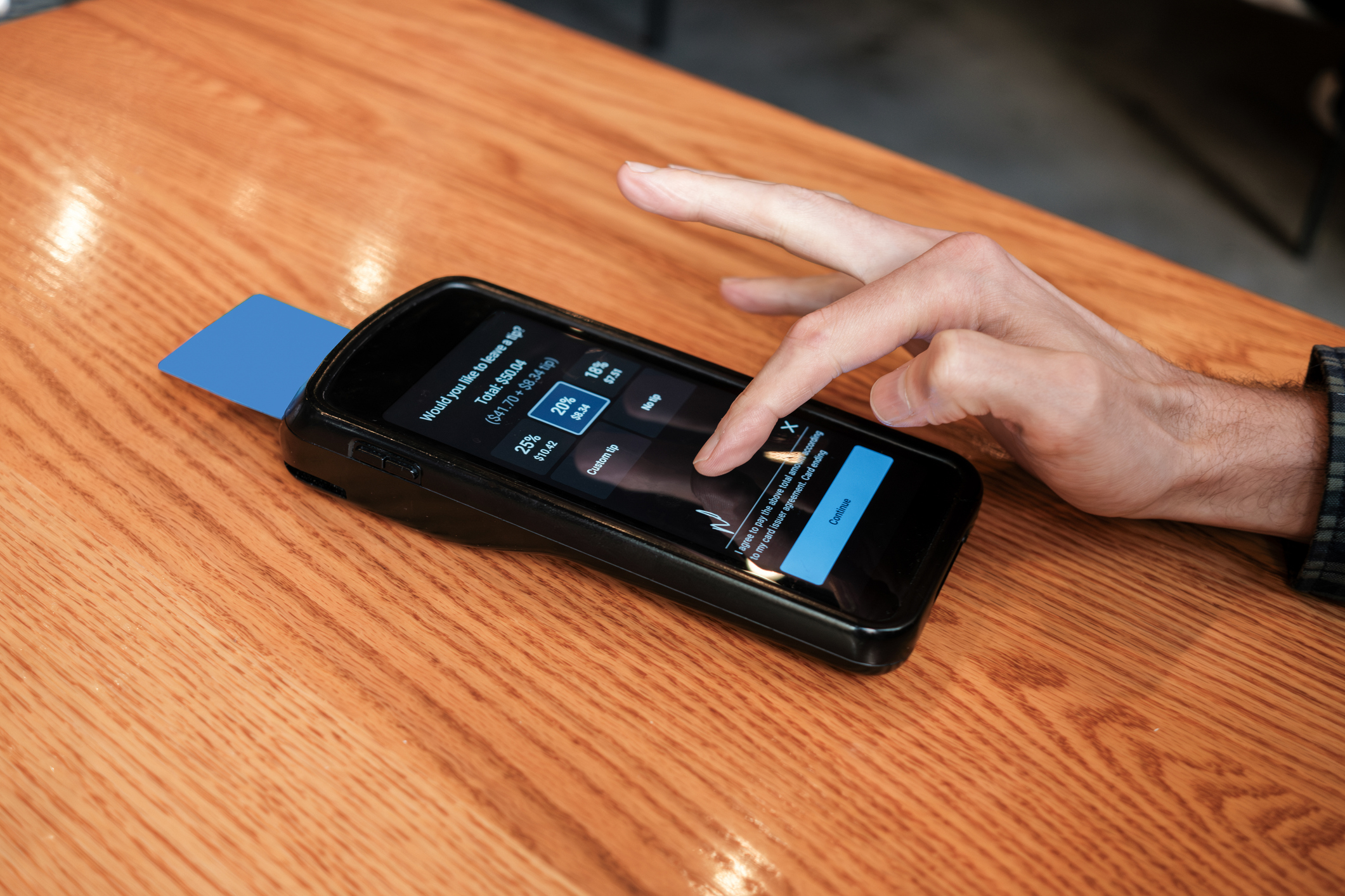 Person using a phone to pay at a restaurant, with a credit card inserted into a mobile card reader