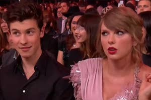 Two individuals sitting at an event — Shawn Mendes and Taylor Swift — the person on the right wearing a pink fringed outfit