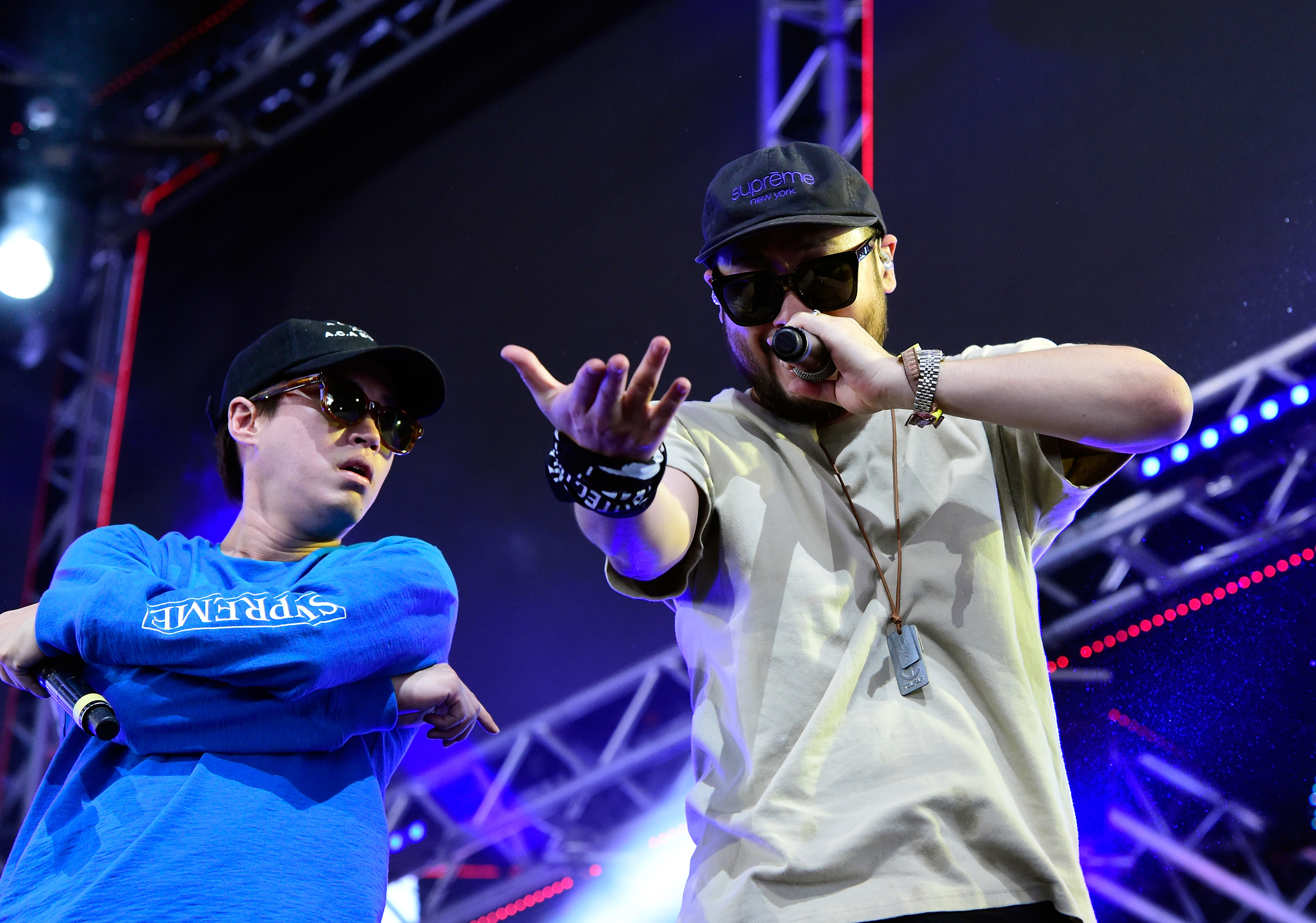 Epik High en el escenario de Coachella, uno extendiendo la mano, otro con micrófono, con gorras y ropa casual