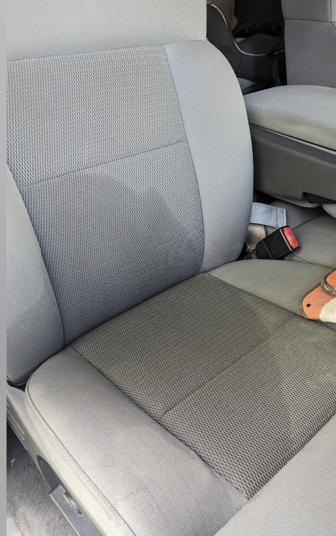 Vehicle seat with a textured cover and a plush toy visible on the seat edge