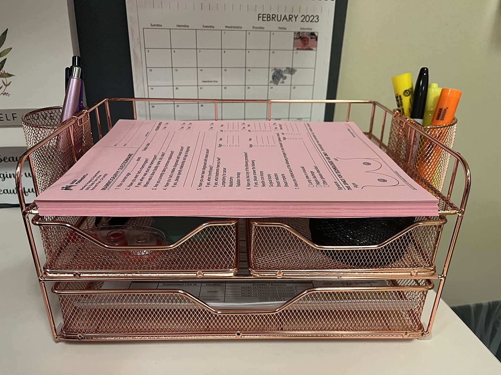 a reviewer photo of the rose gold desk organizer with documents and office supplies, atop a desk