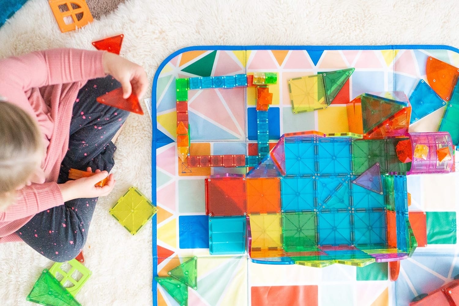 Child playing with colorful magnetic building blocks on floor
