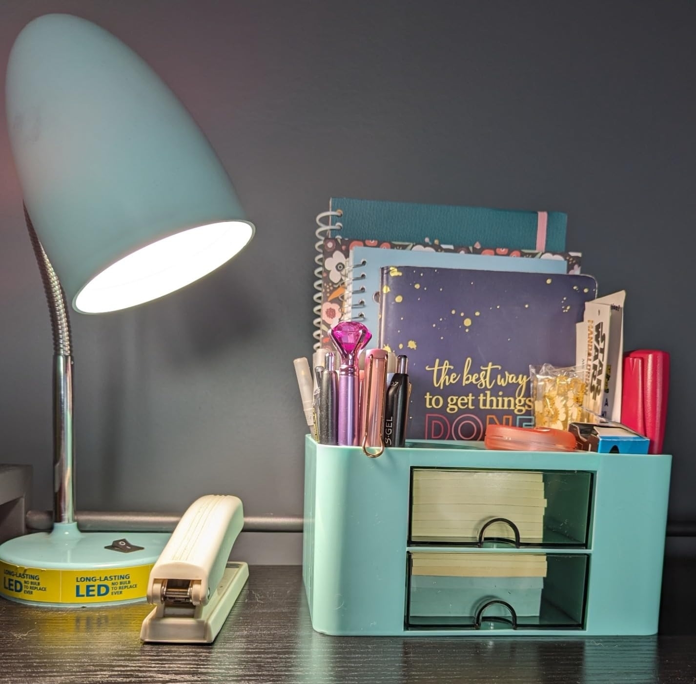 a reviewer photo of the aqua blue desk organizer with stationery, sticky notes, lamp, and planner