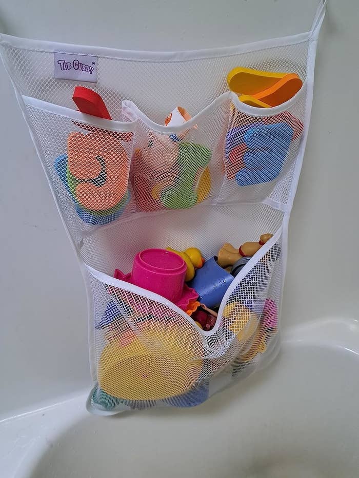 Mesh organizer with various children&#x27;s bath toys hung in a bathtub. Ideal for tidy storage