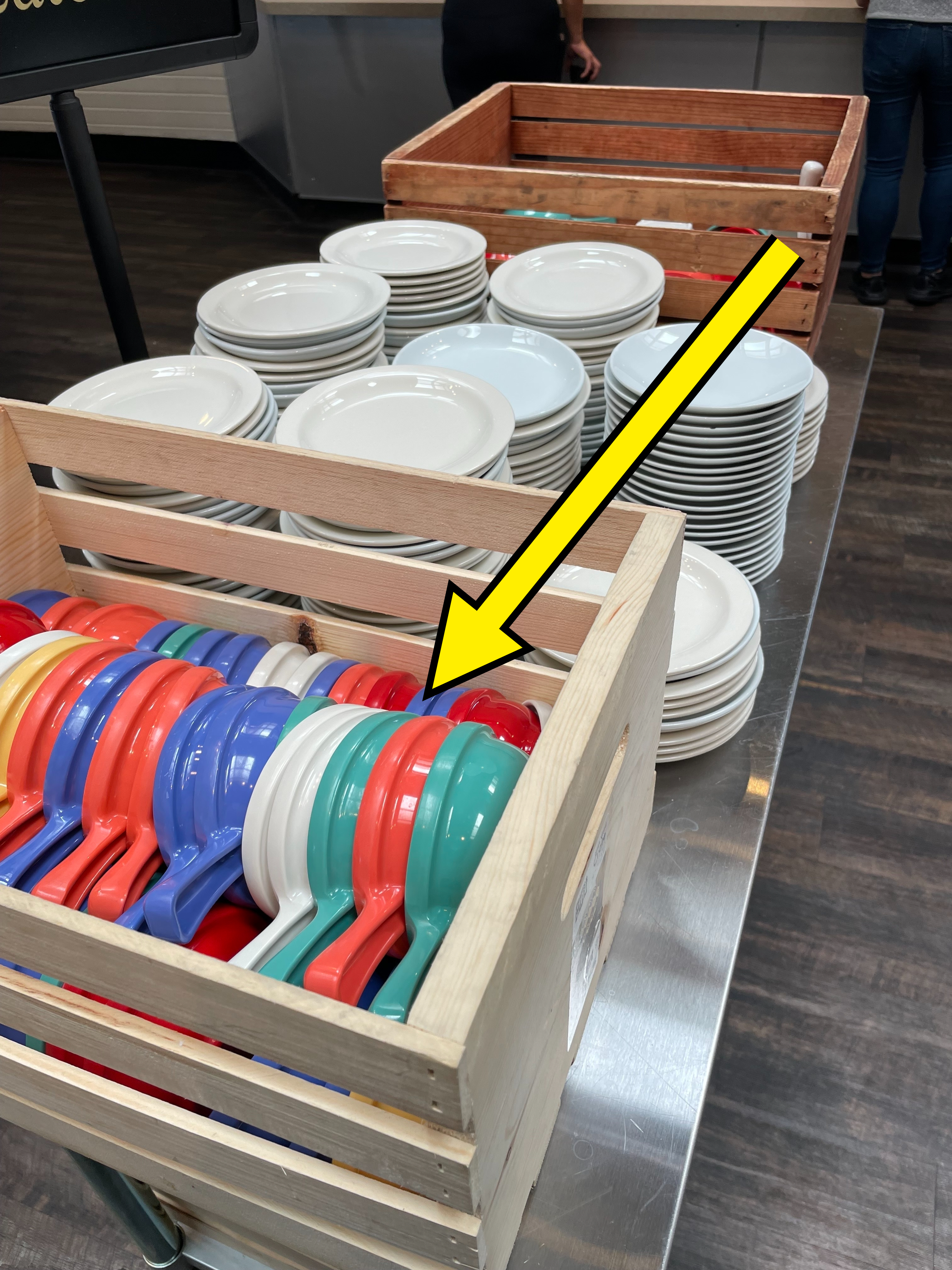 Stacks of white plates and colorful bowls in a wooden cart, ready for serving