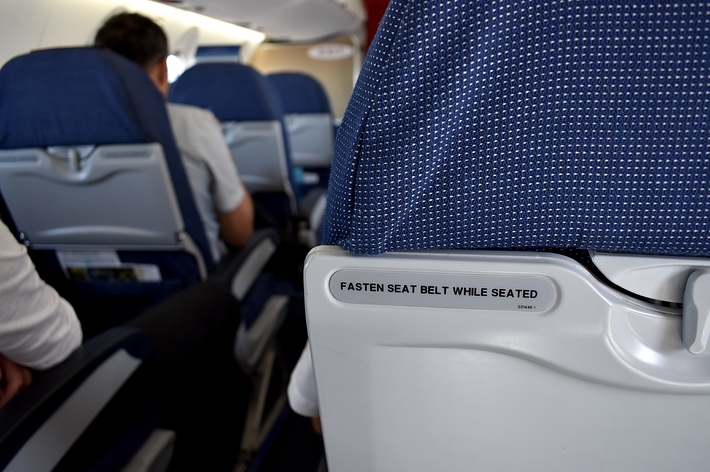 機内での座席と「FASTEN SEAT BELT WHILE SEATED」と書かれたサイン。