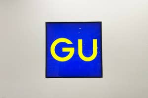 Artwork with the letters "GU" on a blue background, displayed in a simple frame on a white wall