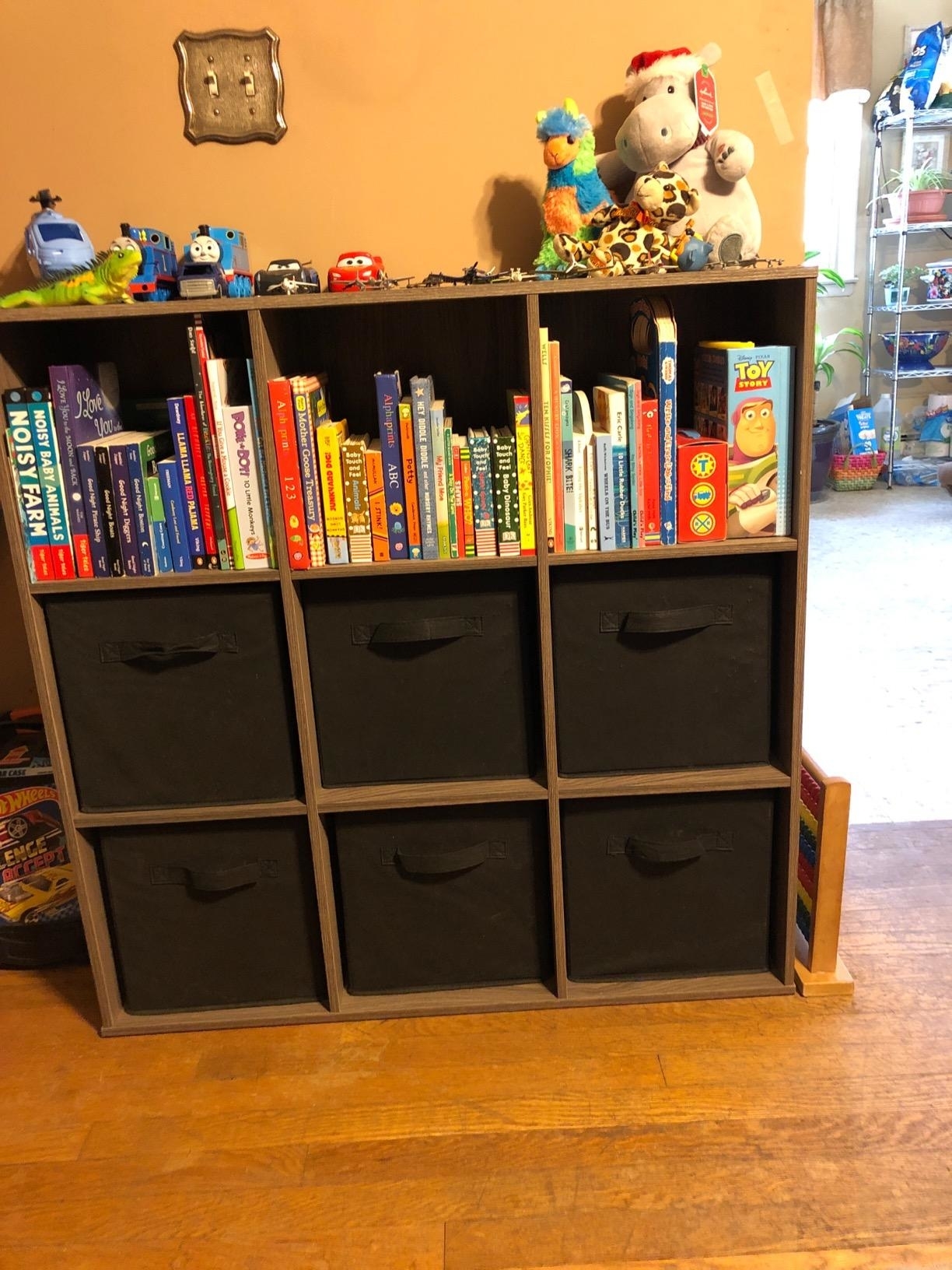 Bookshelf with children’s books and toys, including a Toy Story theme on top shelf