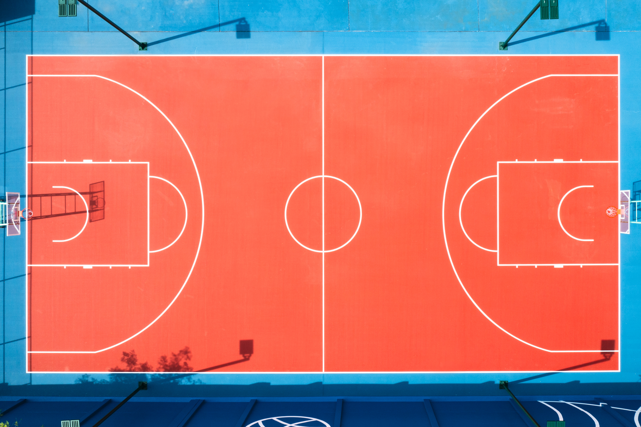 Aerial view of an empty basketball court with clear boundary lines and hoops at either end