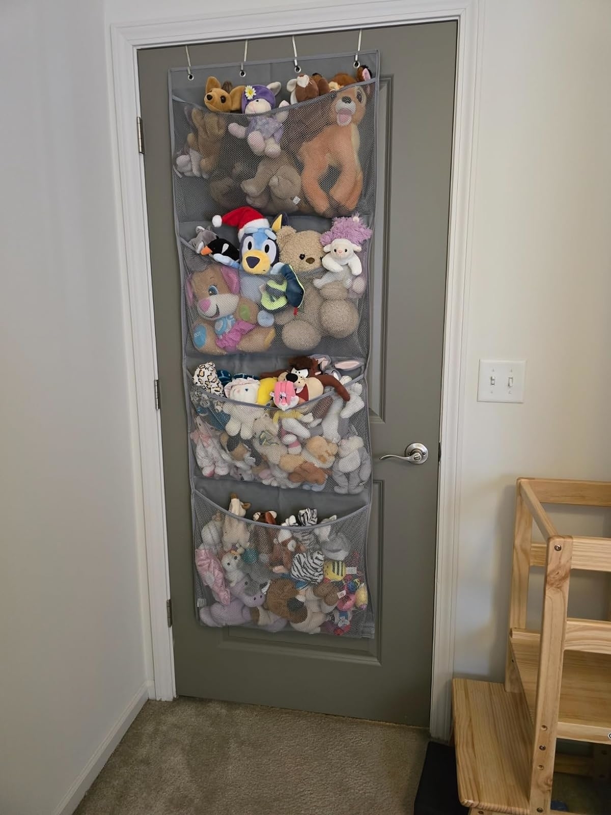 A hanging organizer on a door filled with various plush toys, useful for space-saving storage solutions
