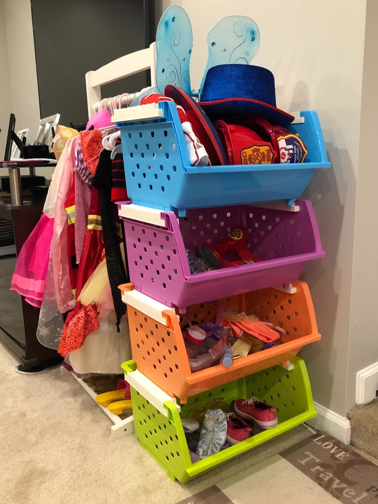 Stacked toy bins with various children&#x27;s dress-up clothes and accessories
