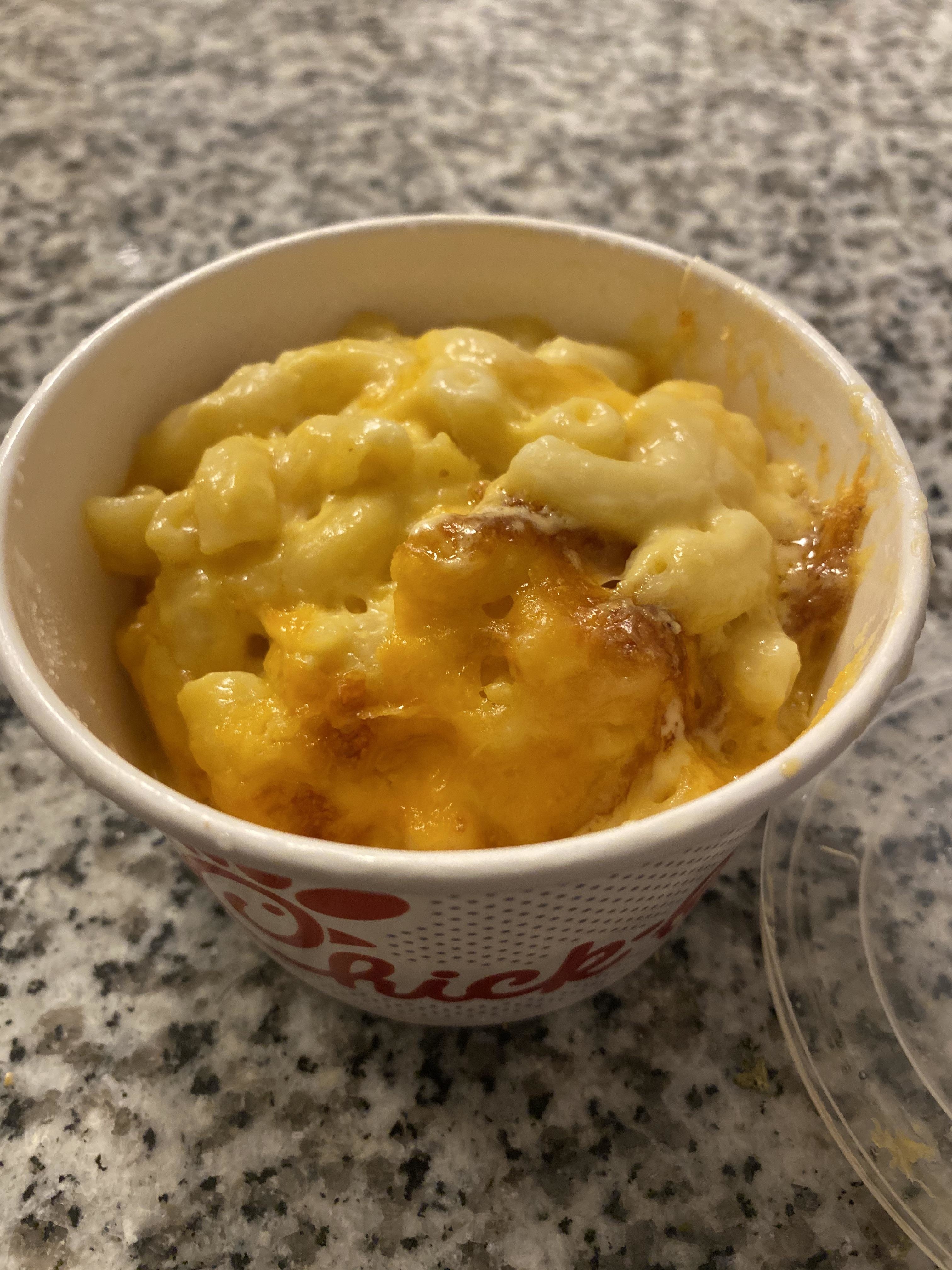 A bowl of creamy macaroni and cheese on a speckled countertop