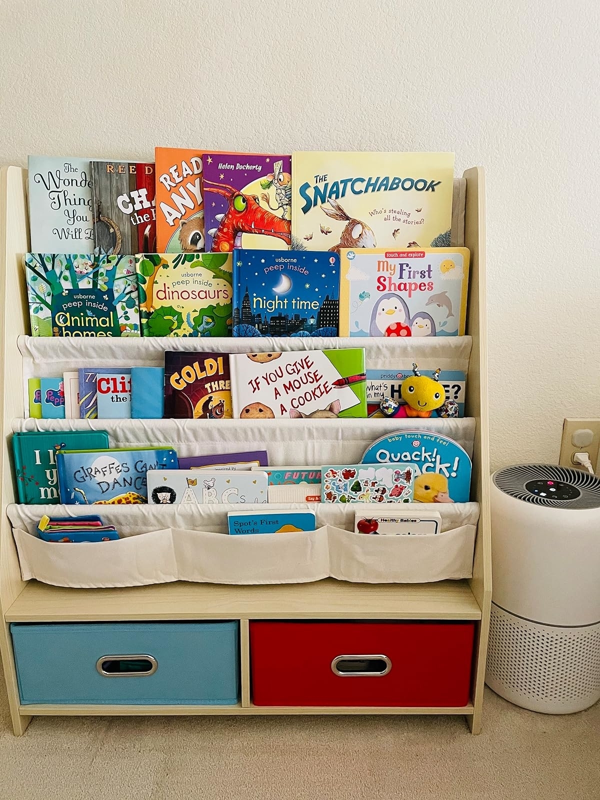 Bookshelf with assorted children&#x27;s books and a play area with storage bins