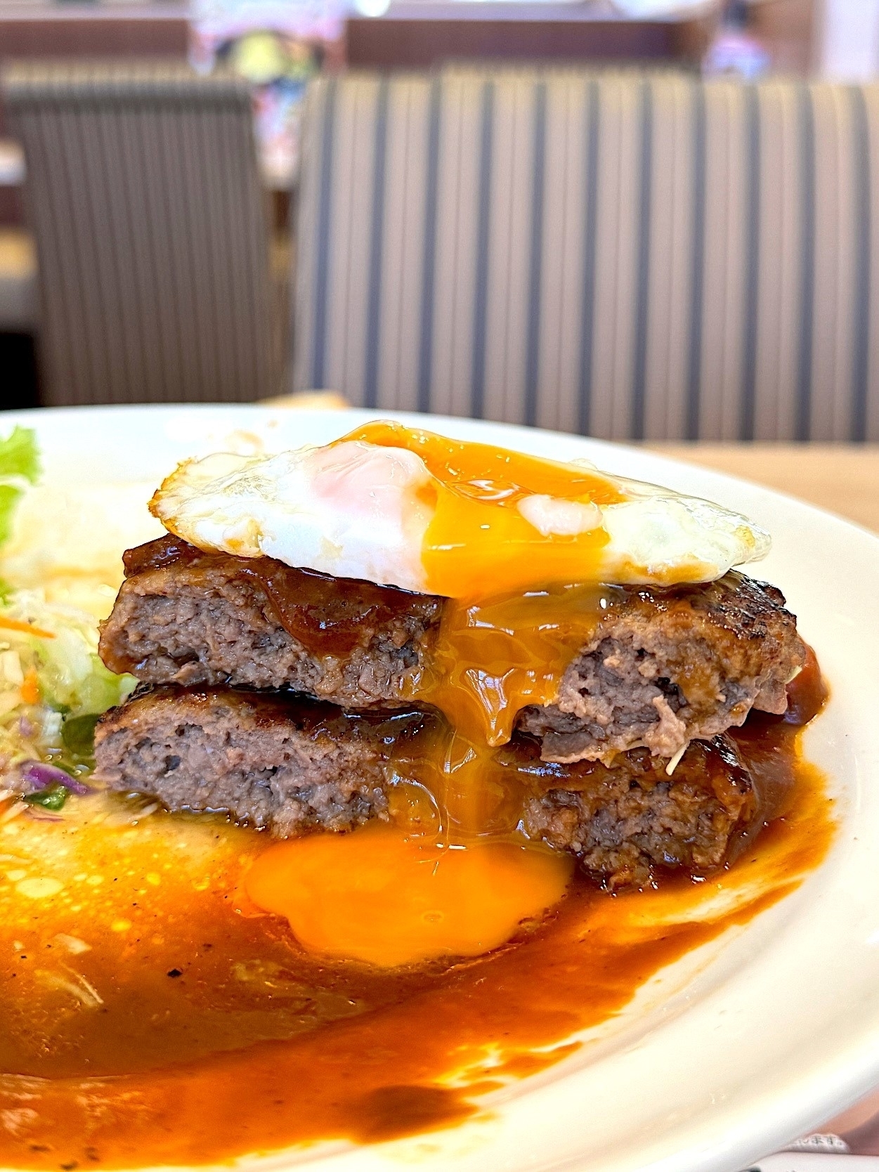 目玉焼きがのったハンバーグステーキ、流れる黄身が見えます。