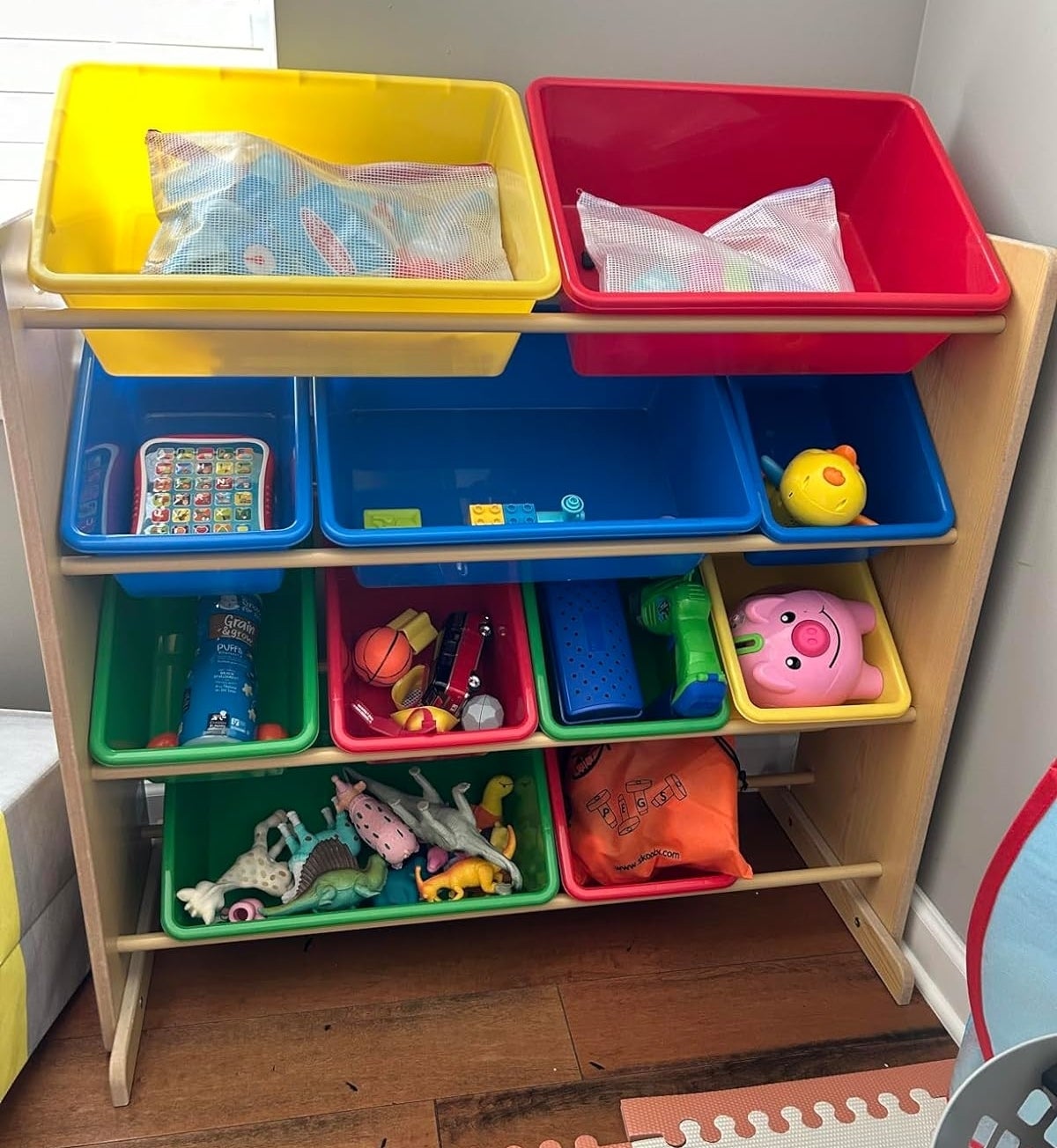 A toy organizer with various bins holding toys and children&#x27;s items, in a play area