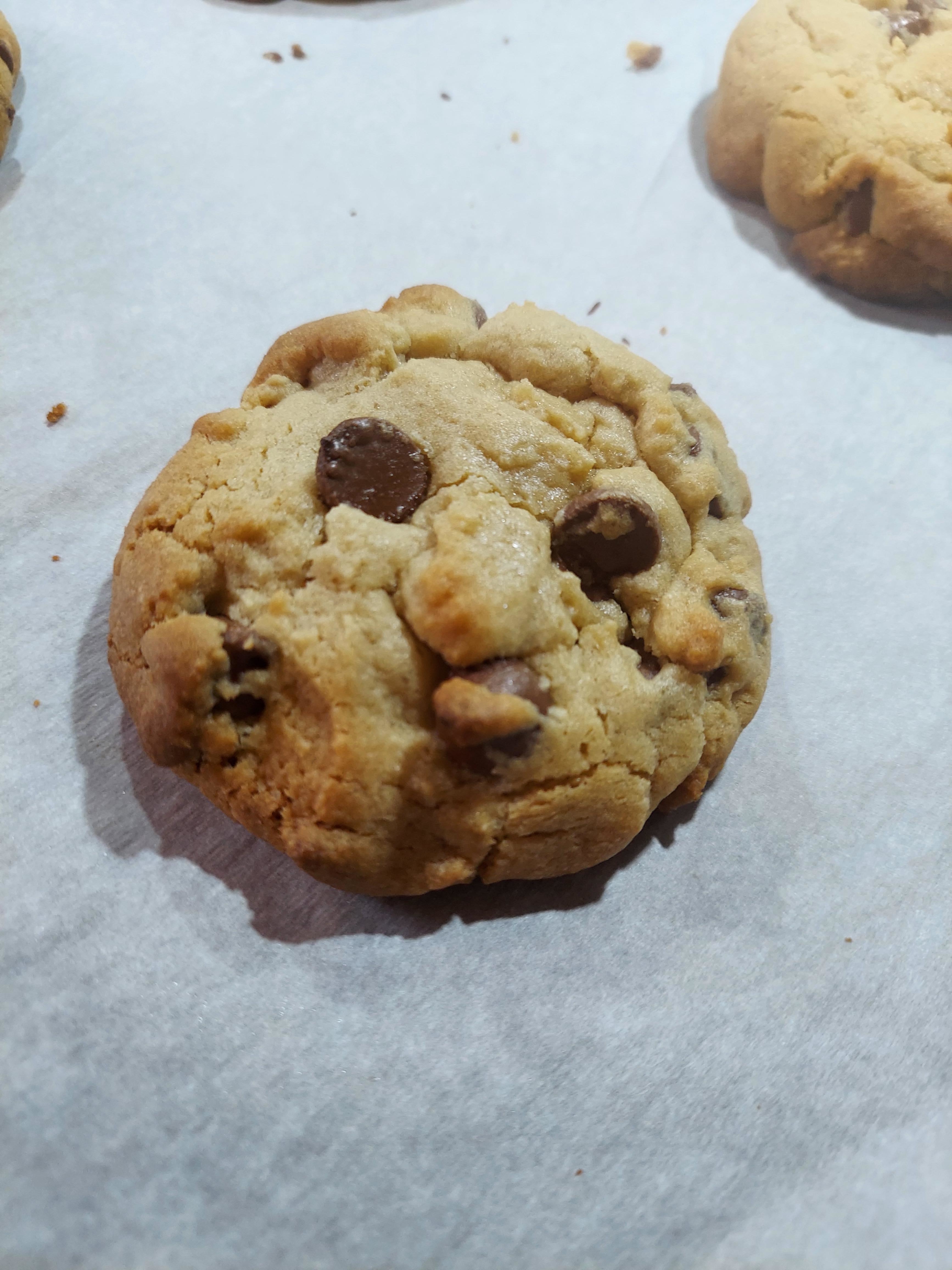 A freshly baked chocolate chip cookie on parchment paper