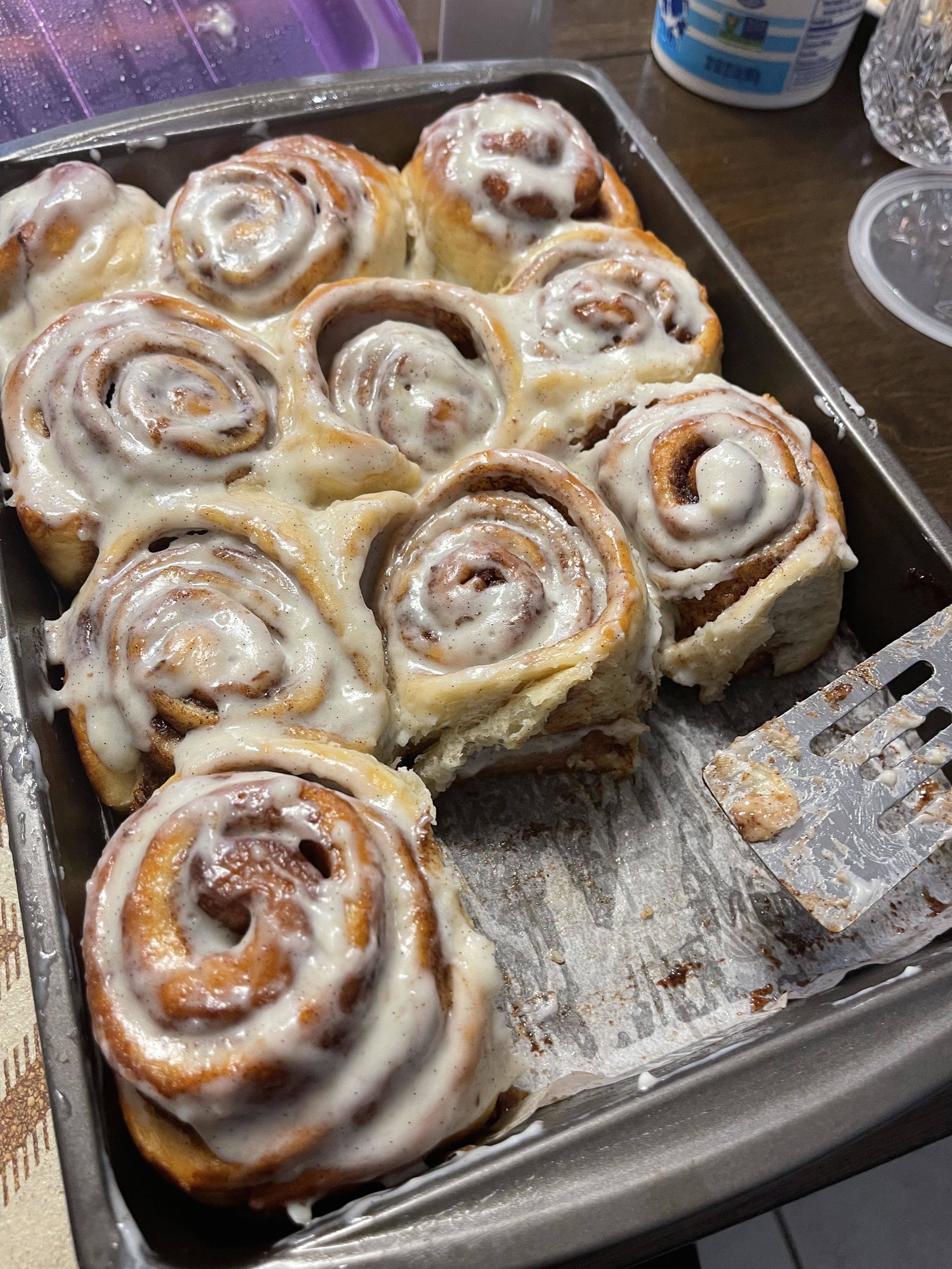 Tray of freshly baked cinnamon rolls with one partially taken out