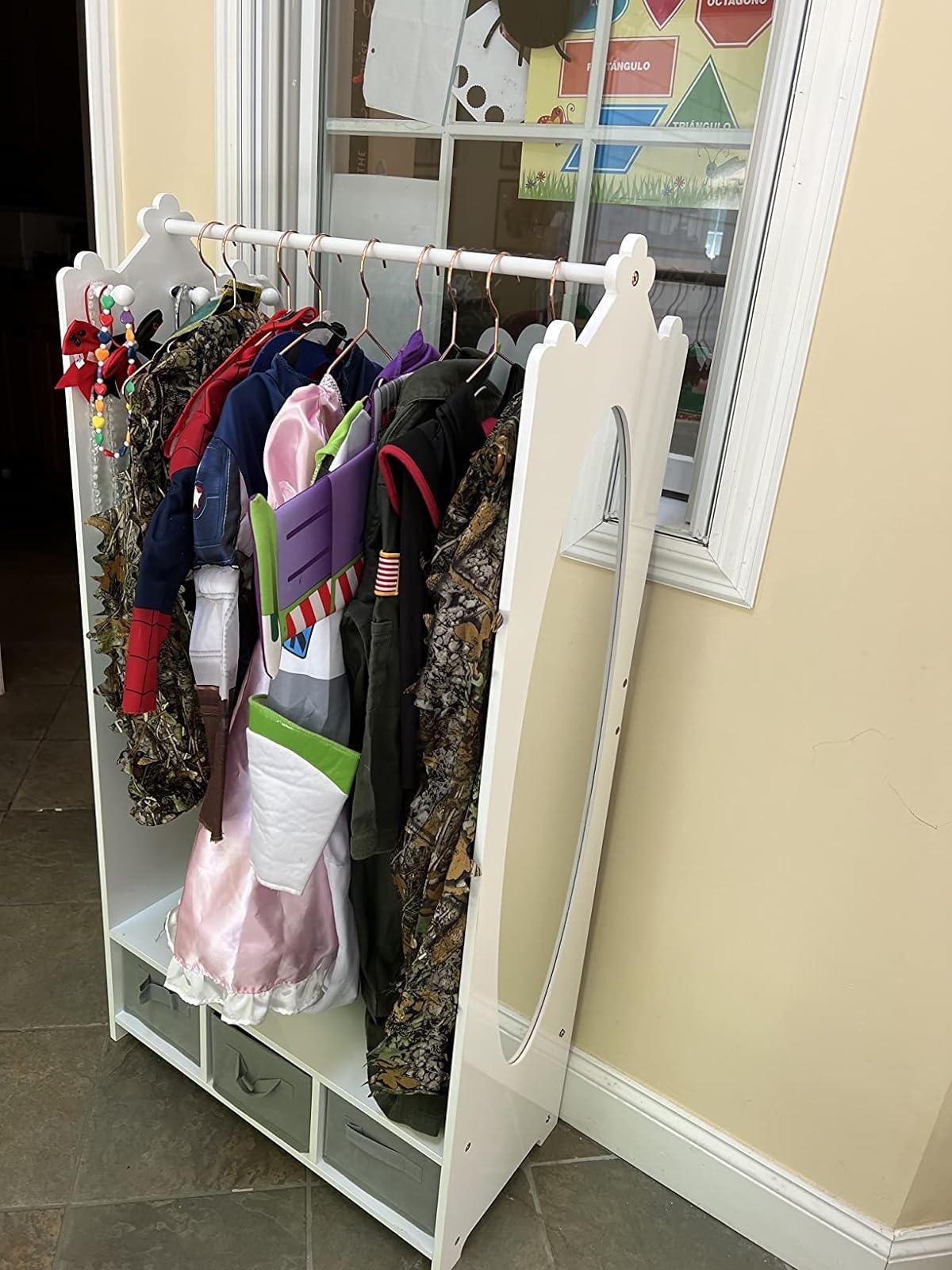 A rack with a variety of children&#x27;s costumes including a fairy princess and camouflage outfits