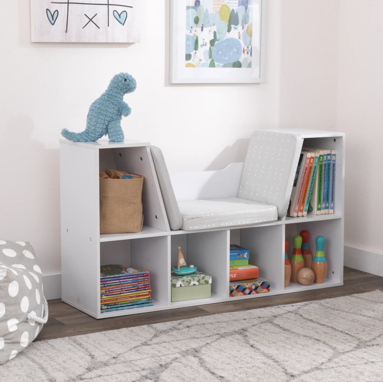 Child&#x27;s room with a white storage bench holding books and toys, with a dinosaur plush on top
