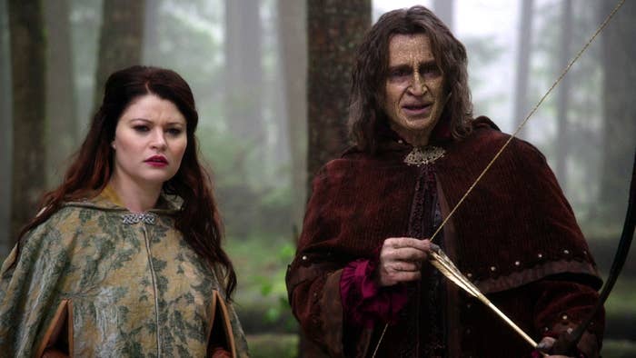 Belle and Rumplestiltskin from the show &#x27;Once Upon a Time&#x27; standing in a forest with a bow and arrow