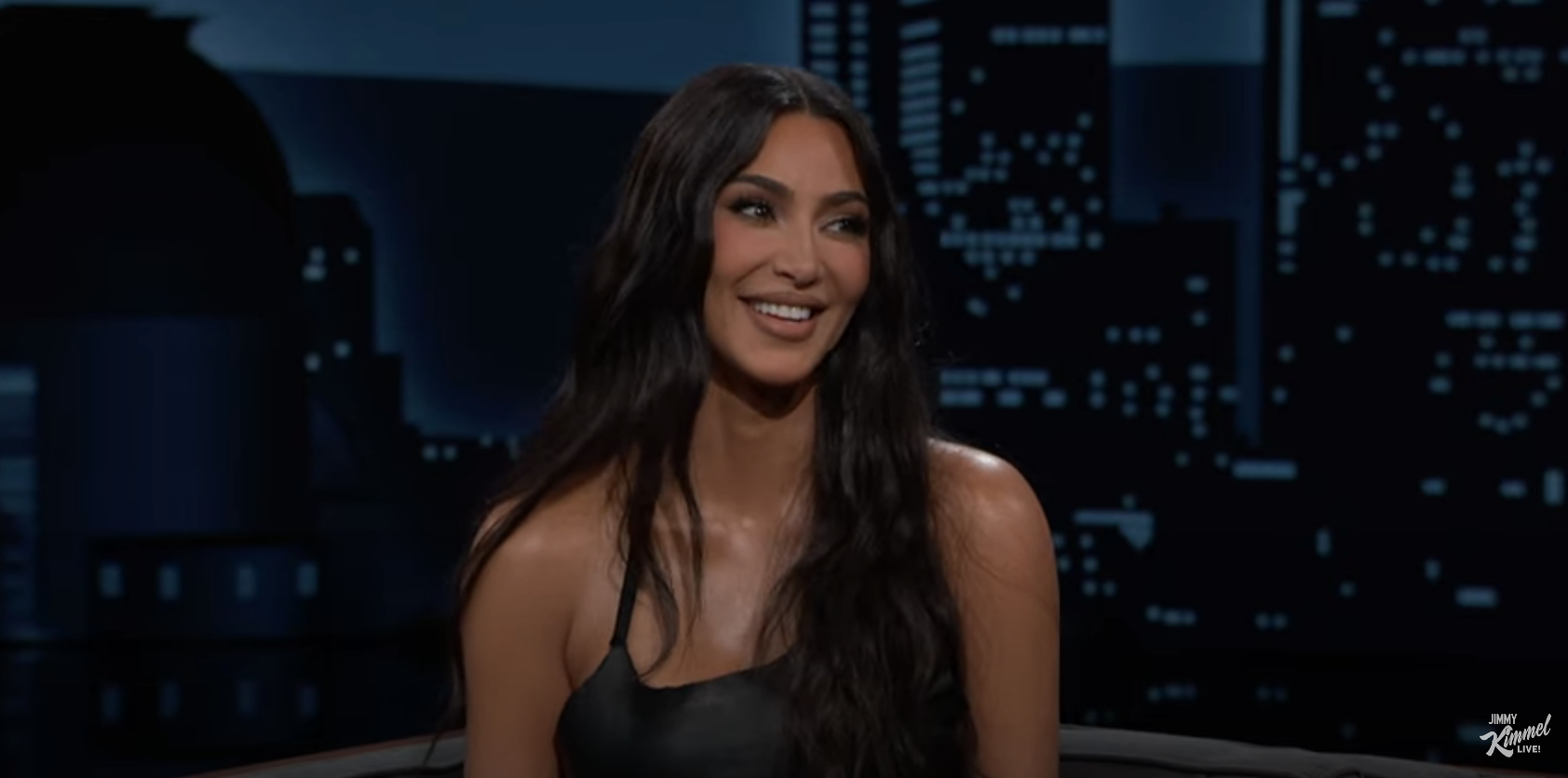 Person in a black top smiling on a talk show set